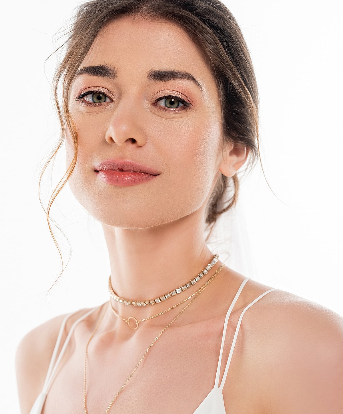 Young woman with layered necklaces and natural makeup.