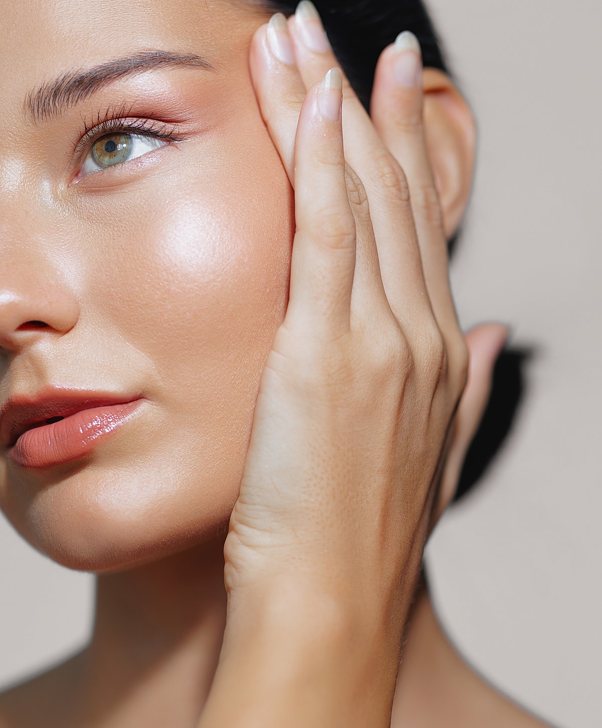Close-up of a woman's glowing skin and hand.