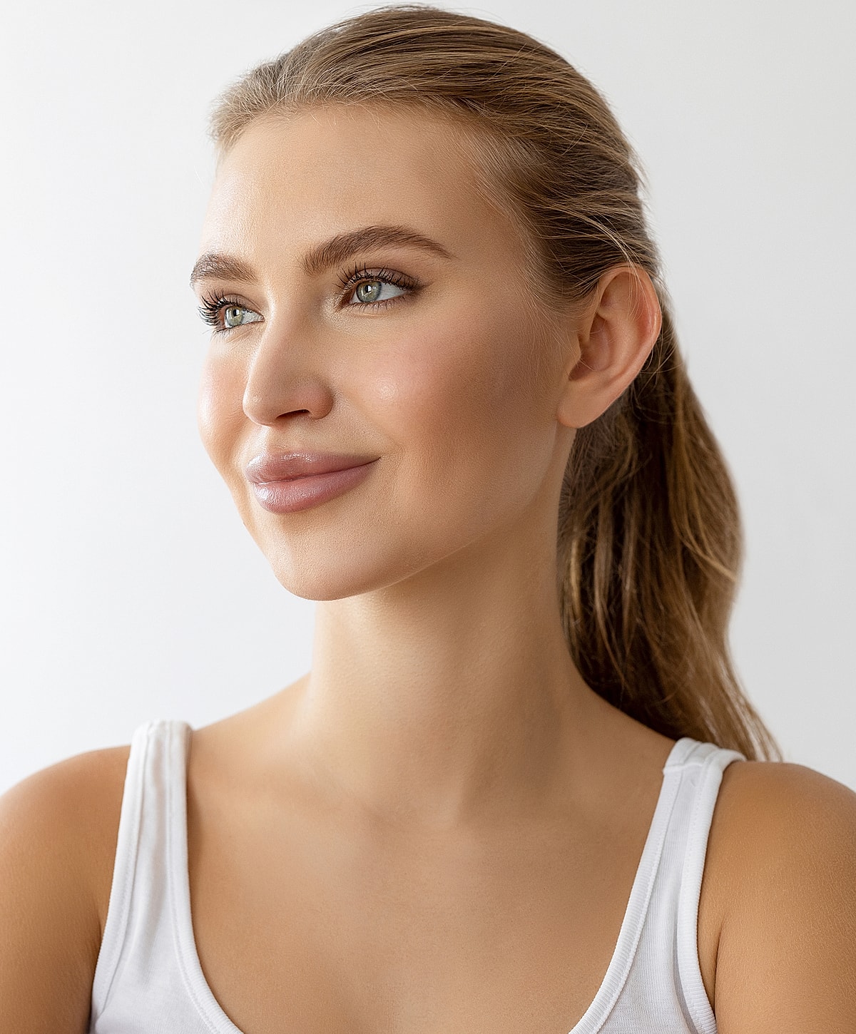 Smiling woman with long ponytail and natural makeup.