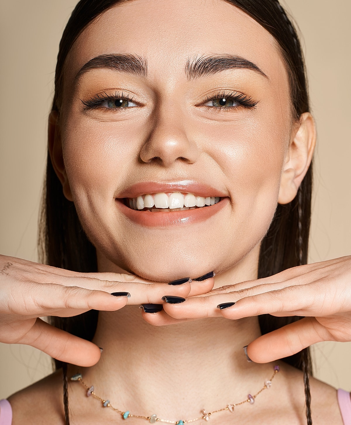 Smiling woman with hands under chin.