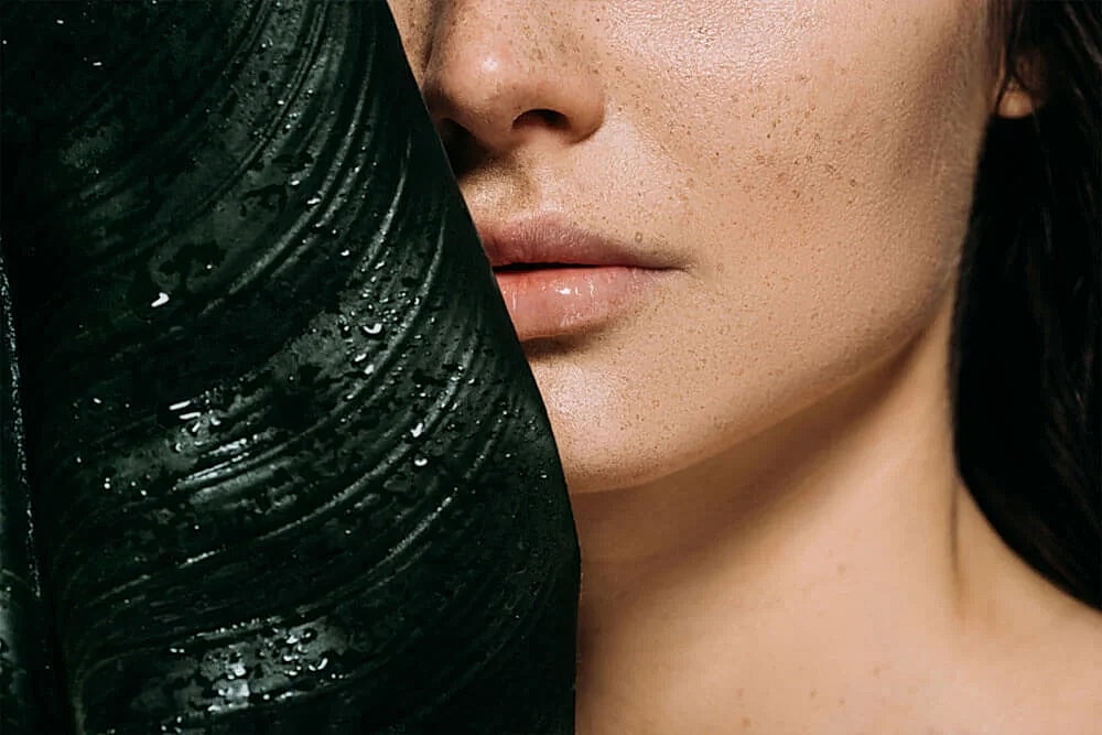 Close-up of a woman's face with wet fabric.